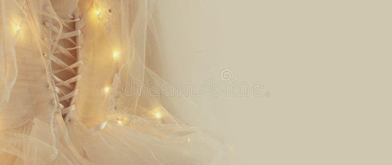 Beautiful white wedding dress and veil on chair with garland lights