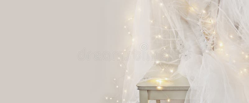 Beautiful white wedding dress and veil on chair with gold garland lights