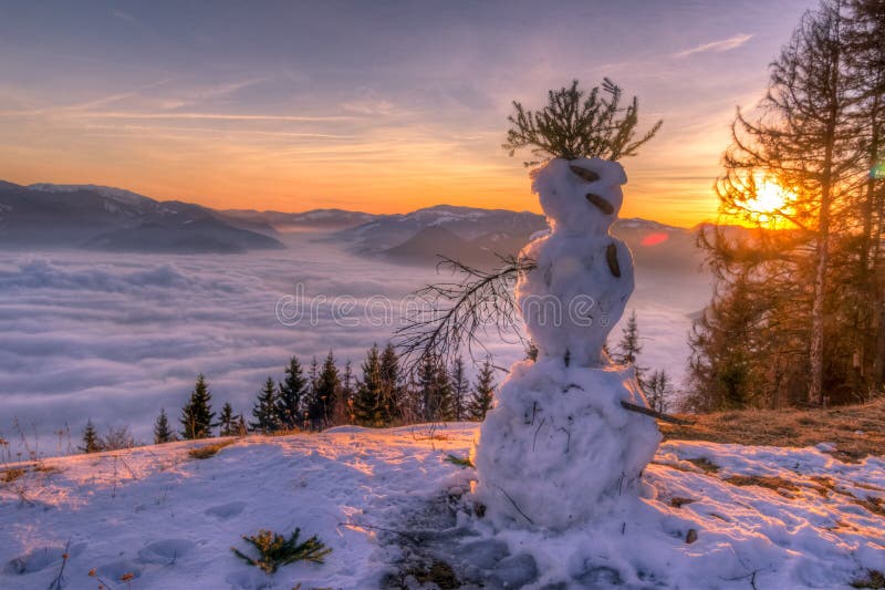 Beautiful winter sunset with snowman in foreground