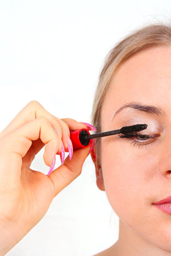 Beautiful woman applying mascara on her eyelashes