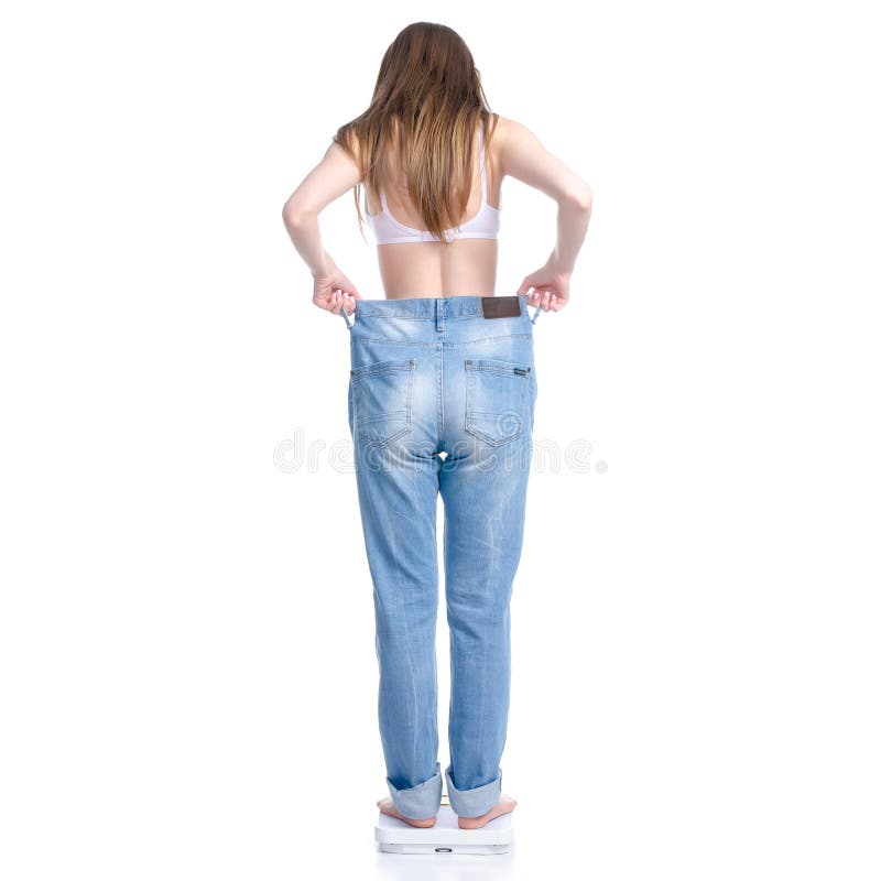 Beautiful woman in big jeans on weighing-machine, weight loss slimming royalty free stock photo Beautiful woman in big jeans on weighing-machine, weight loss slimming royalty free stock photo