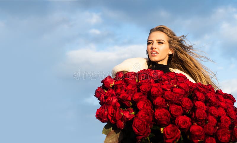 Beautiful woman with red roses. Gift with love. Beautiful smiling girl  holding large bouquet of red roses on black background. Beautiful woman  with red rose bouquet. Stock Photo