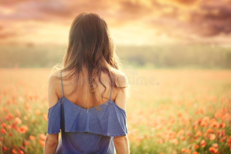 Beautiful woman in a blue dress in a wheat field at sunset from the back, warm toning, happiness and a healthy lifestyle stock photo Beautiful woman in a blue dress in a wheat field at sunset from the back, warm toning, happiness and a healthy lifestyle stock photo