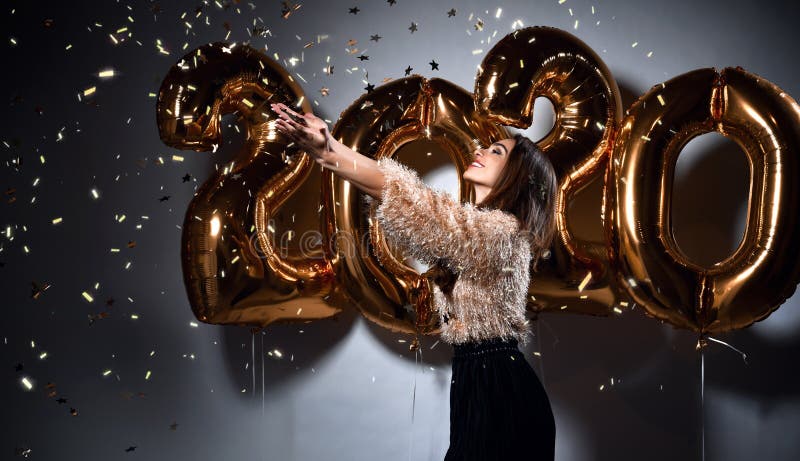 Beautiful woman celebrating New Year with gold 2020 balloons. Happy gorgeous girl in stylish sexy party dress royalty free stock images Beautiful woman celebrating New Year with gold 2020 balloons. Happy gorgeous girl in stylish sexy party dress royalty free stock images