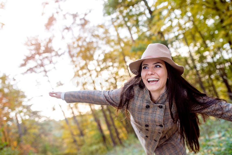 Beautiful woman in checked coat and hat, autumn forest