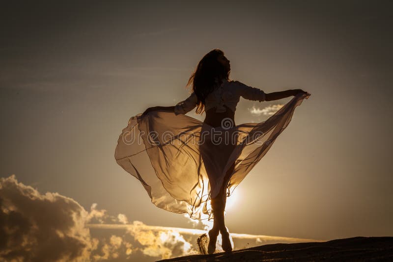 Bella donna che balla sulla spiaggia al tramonto.