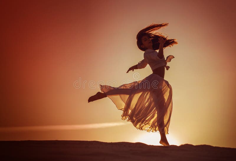 Beautiful woman dancing at sunset