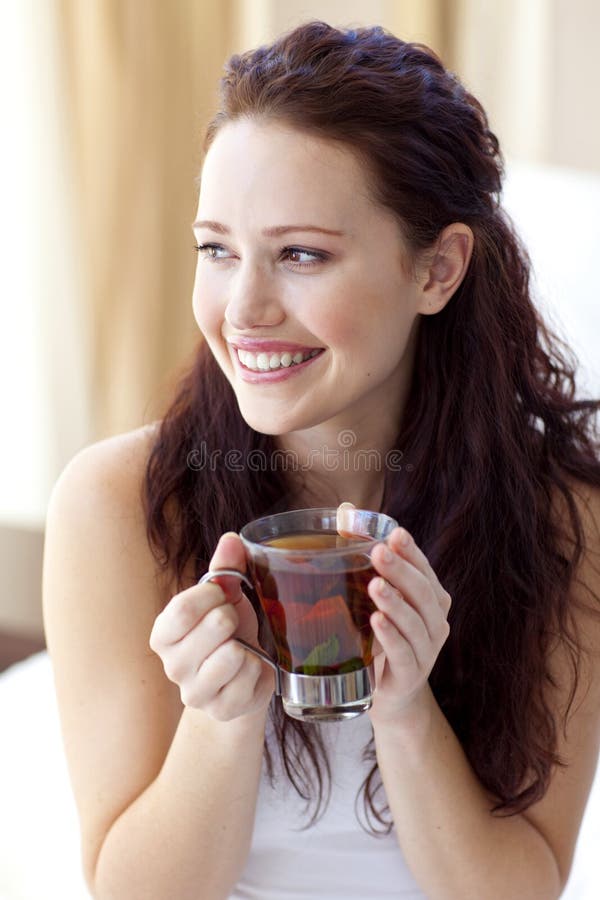 Beautiful woman drinking a cup of tea in bed royalty free stock image