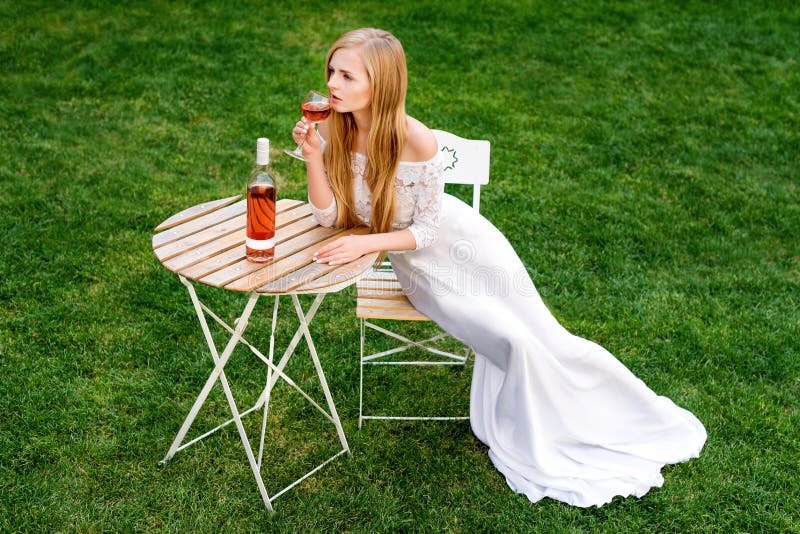 Beautiful woman drinking wine in outdoors cafe. Portrait of young blonde beauty in the vineyards having fun, enjoying a stock photo Beautiful woman drinking wine in outdoors cafe. Portrait of young blonde beauty in the vineyards having fun, enjoying a stock photo