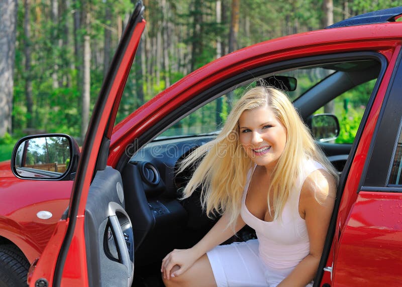 Beautiful woman driver in red shiny car