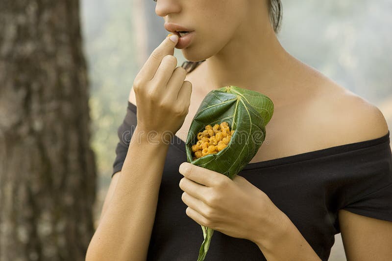 Beautiful woman eating wild raspberry in the forest