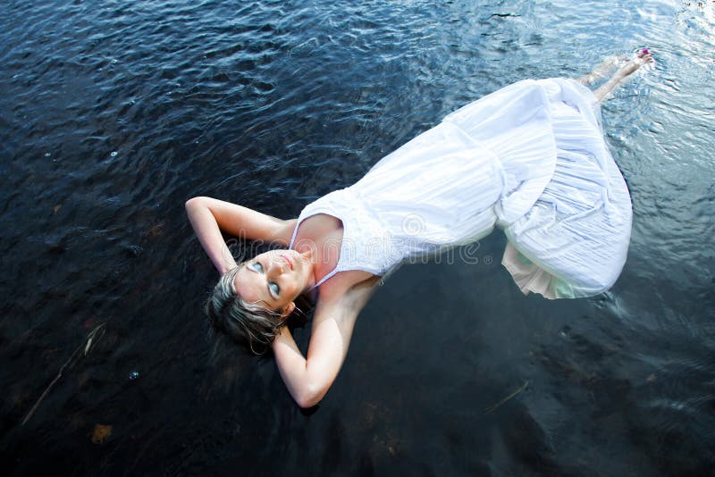 Beautiful woman floating in blue river