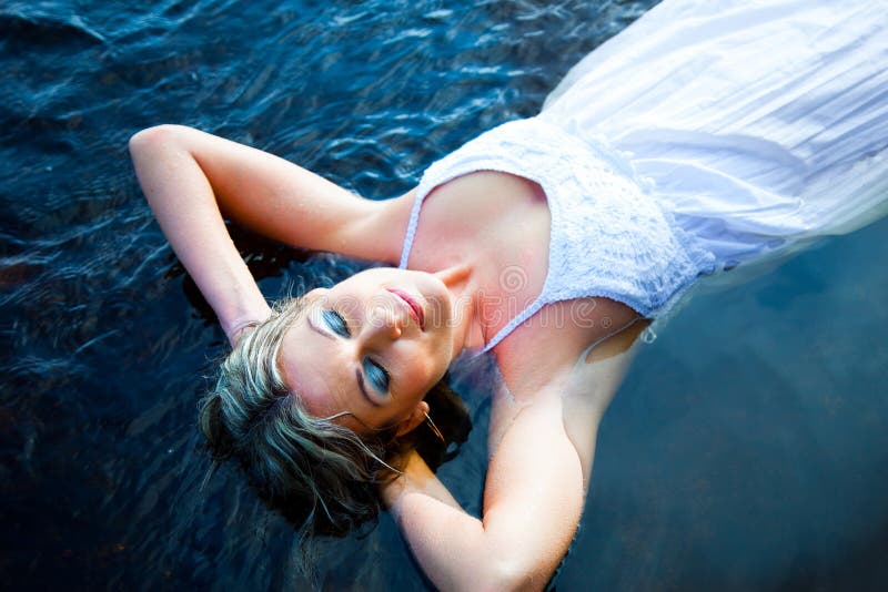 Beautiful woman floating in blue river stock photo