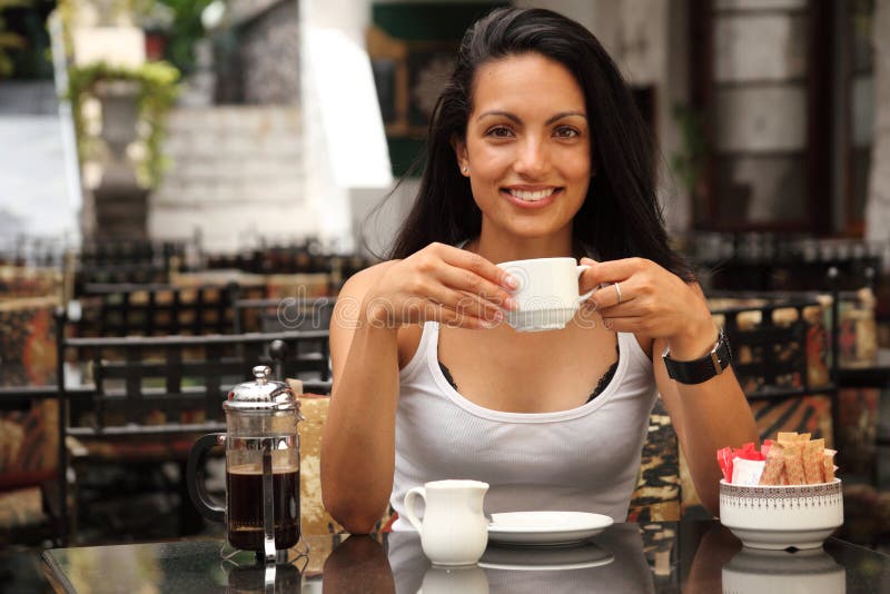 Beautiful woman having coffee in courtyard cafe