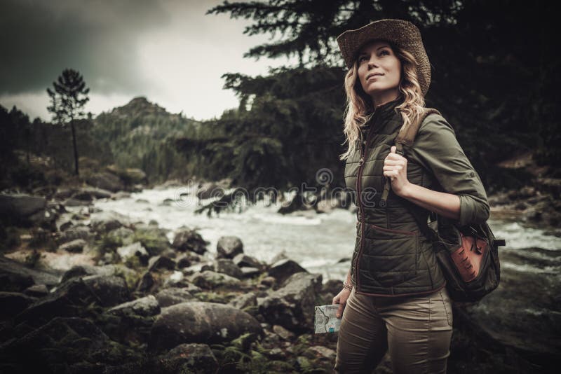 Beautiful woman hiker near wild mountain river.