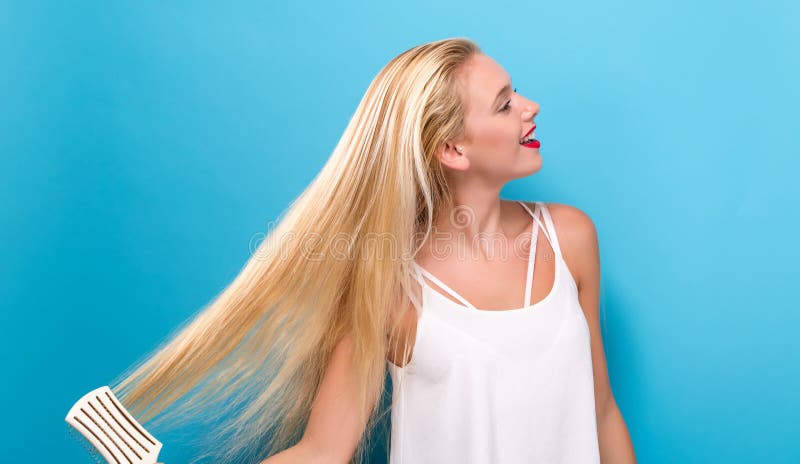 Beautiful woman holding a hairbrush on solid background