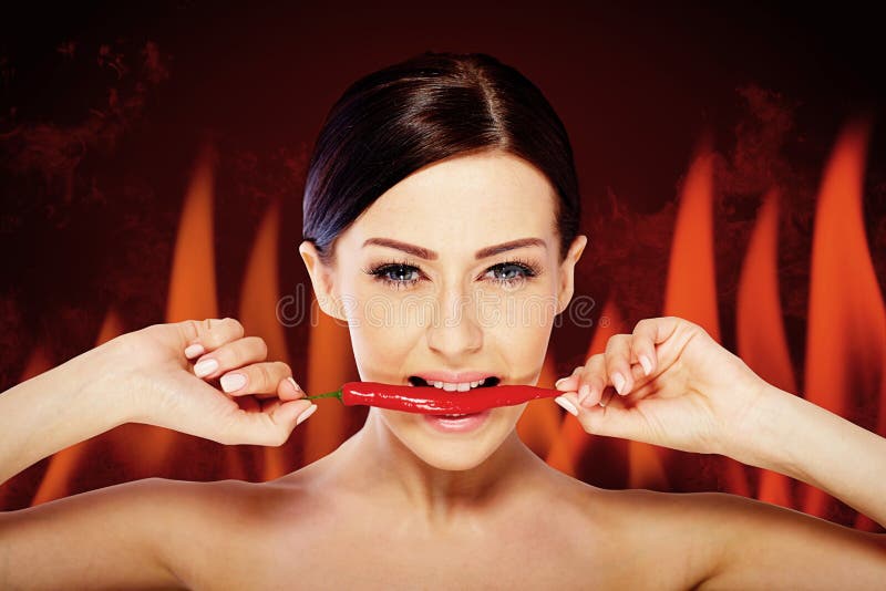 Beautiful woman with a hot spicy chili. fire background royalty free stock photography Beautiful woman with a hot spicy chili. fire background royalty free stock photography