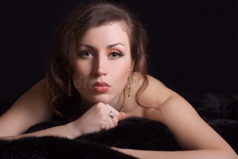 Beautiful woman in jewelry lies on fur