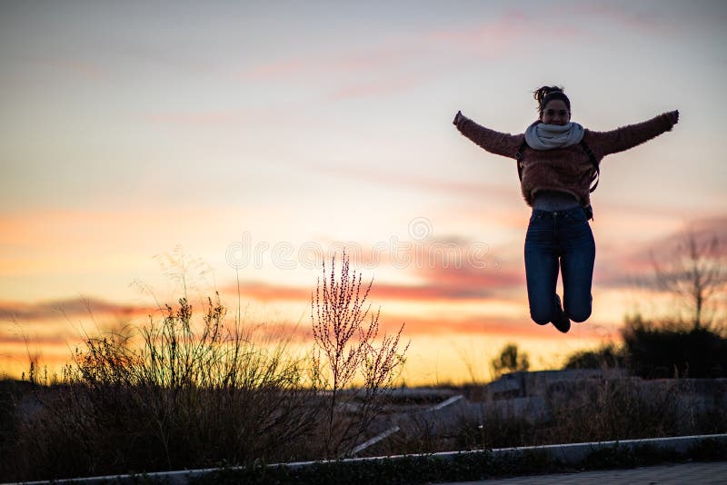Beautiful woman jumping from a concrete block during sunset stock photo Beautiful woman jumping from a concrete block during sunset stock photo