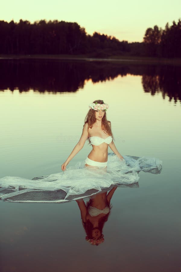 Beautiful woman in a lake at night. Girl at sunset in the lake.