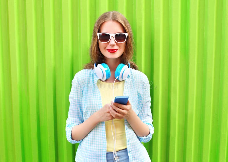 Beautiful woman listens to music in headphones using smartphone over green royalty free stock image Beautiful woman listens to music in headphones using smartphone over green royalty free stock image
