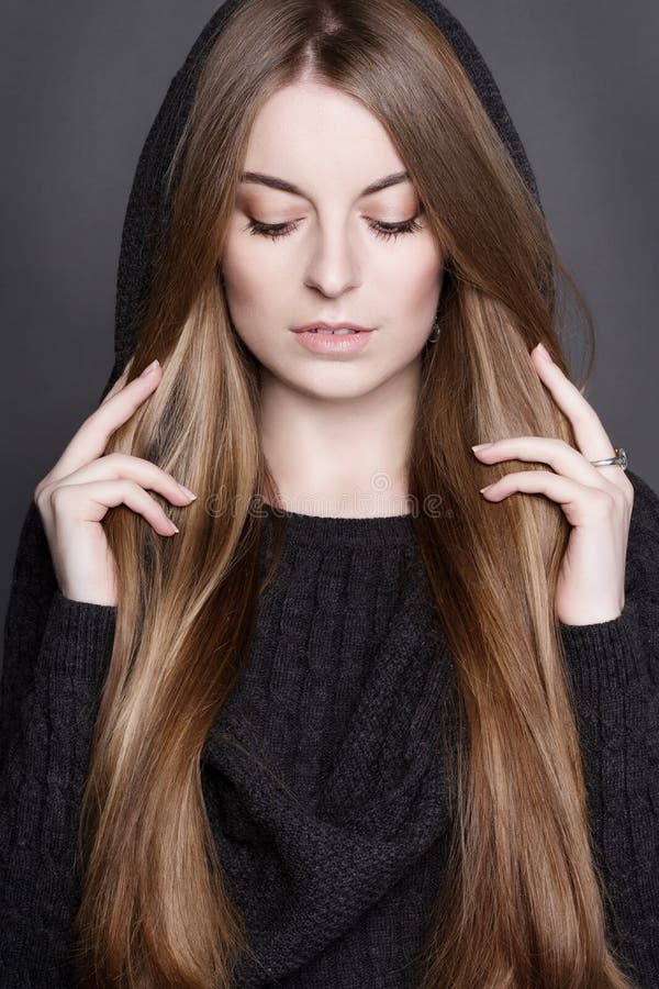 Beautiful woman with long, gorgeous dark blond hair. She is dressed in warm gray knit dress with a hood. stock photos Beautiful woman with long, gorgeous dark blond hair. She is dressed in warm gray knit dress with a hood. stock photos