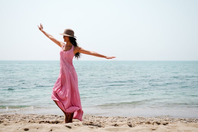 Beautiful woman with long pink dress on the beach