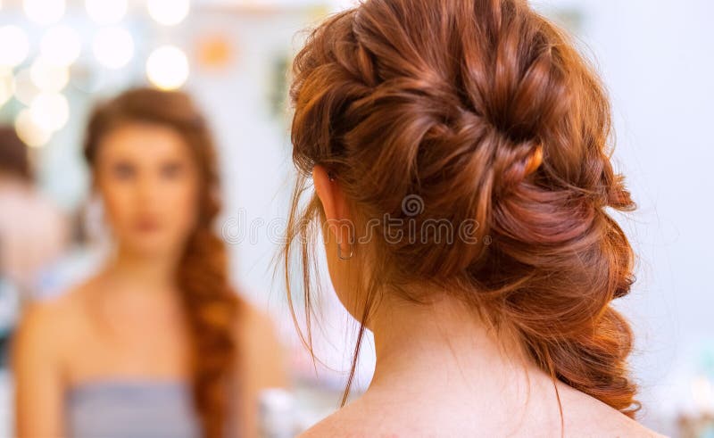 Beautiful woman with long red hair at the beauty salon, hairdresser braided a braid in a beauty salon. Professional hair care and