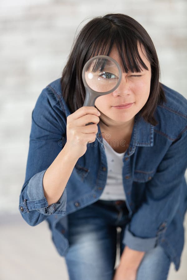 Beautiful Woman Looking at Camera through Magnifying Glass Stock Photo