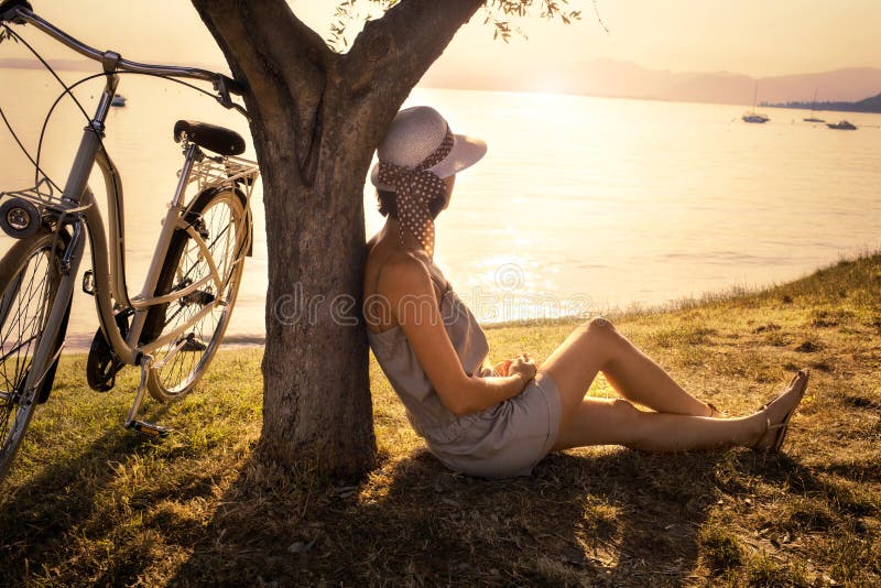 Beautiful woman in love waiting under an olive tree s at sunset