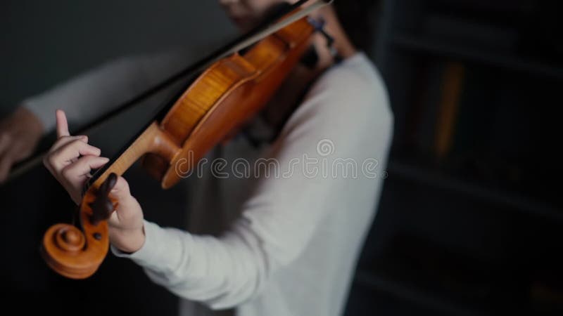 Beautiful woman plays the violin in her home sitting, close- up in slow motion