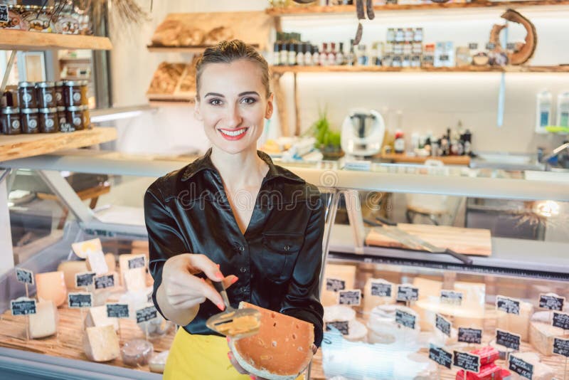 Beautiful woman offering cheese on delicatessen counter