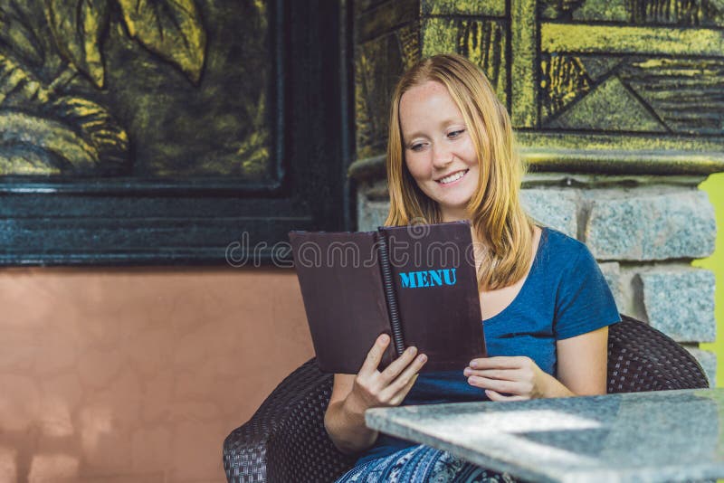 Beautiful Woman Ordering from Menu in Restaurant and Deciding What To ...