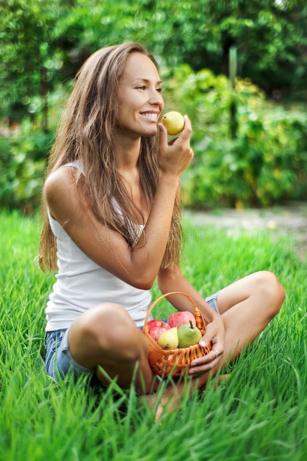 Krásná žena s piknik postýlka jíst hrušky na zelené trávě.