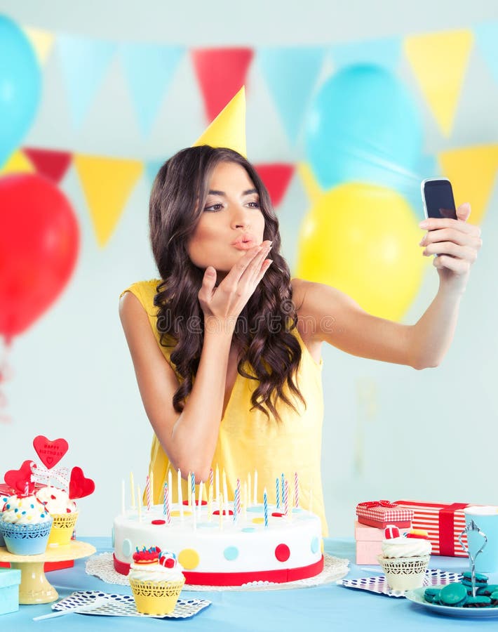 Beautiful woman with phone at party, sending a kiss