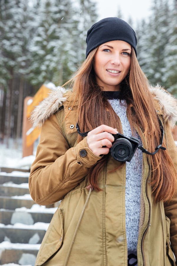 Beautiful woman with photo camera standing on stairs in winter