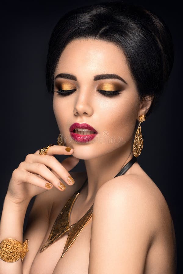 Beautiful woman portrait. Young lady posing with gold jewelry.