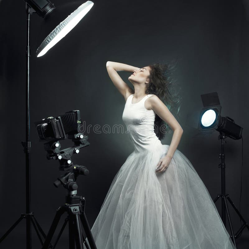 Giovane e bella donna in abito bianco in posa nelle foto di studio.