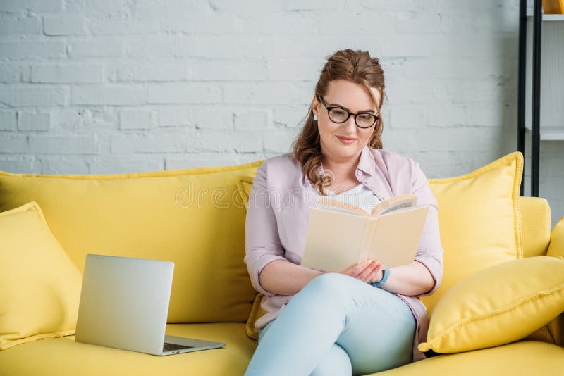 beautiful woman reading book and studying on sofa