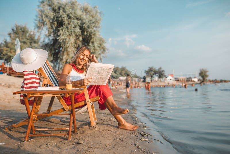 Beautiful woman reading newspaper on the beach