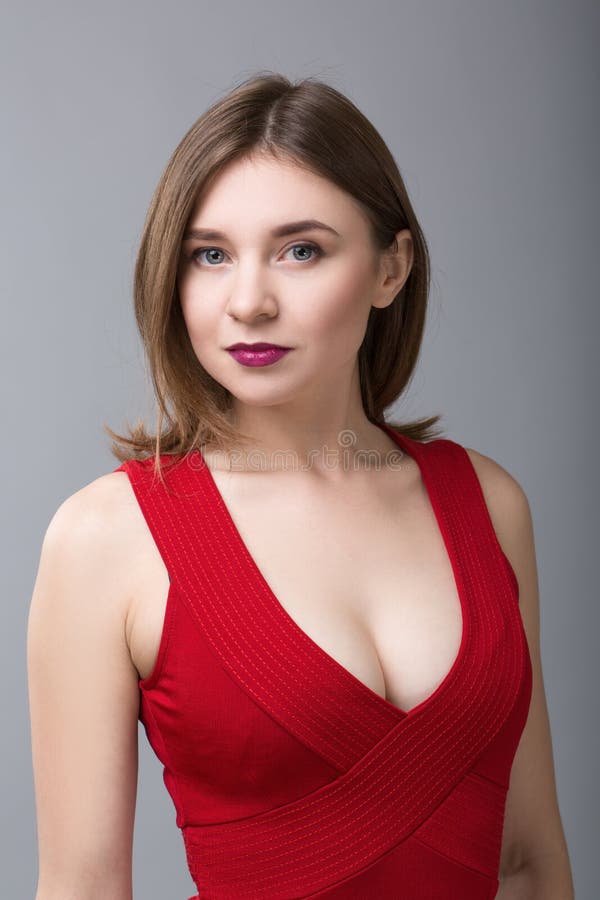 Beautiful woman in red dress looking to the camera on grey background royalty free stock photos Beautiful woman in red dress looking to the camera on grey background royalty free stock photos