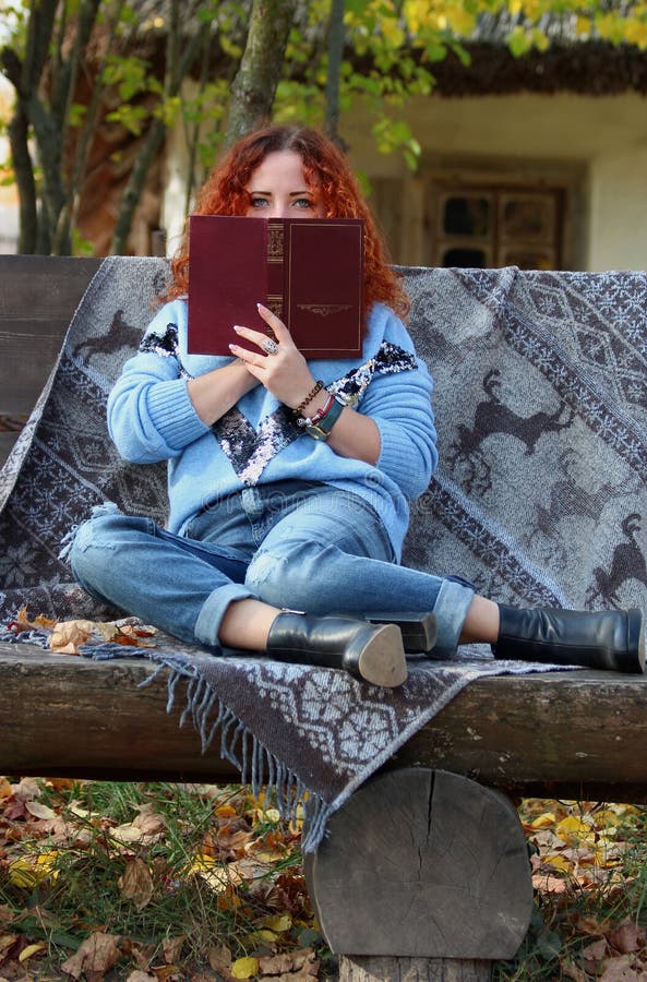 Beautiful Woman with red hair in the autumn park. sitting on a bench with a veil and covering her face with a book. Autumn backgro royalty free stock photos Beautiful Woman with red hair in the autumn park. sitting on a bench with a veil and covering her face with a book. Autumn backgro royalty free stock photos
