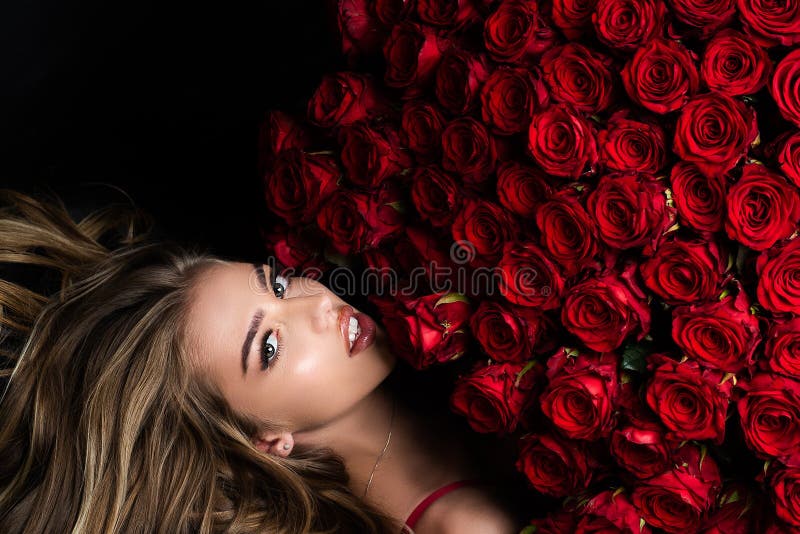 Beautiful woman with red roses. Gift with love. Beautiful smiling girl holding large bouquet of red roses on black