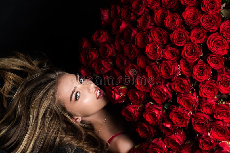 Beautiful woman with red roses. Gift with love. Beautiful smiling girl holding large bouquet of red roses on black