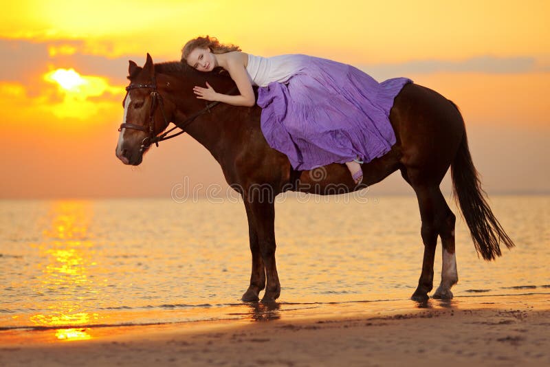 Beautiful woman riding a horse at sunset on the beach. Young beauty girl with a horse in the rays of the sun by the sea.