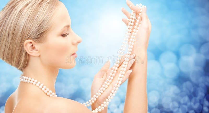 Beautiful woman with sea pearl necklace over blue