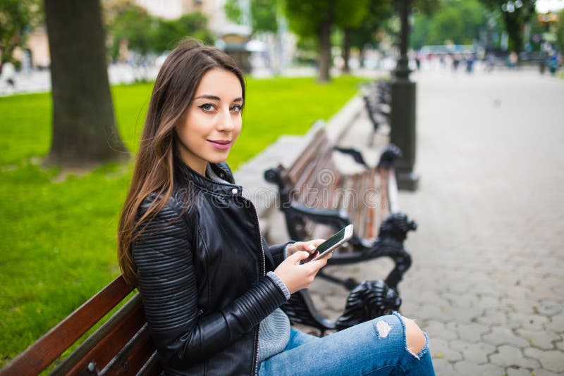 Young Woman With Smartphone Sitting On A Bench Stock Photo 