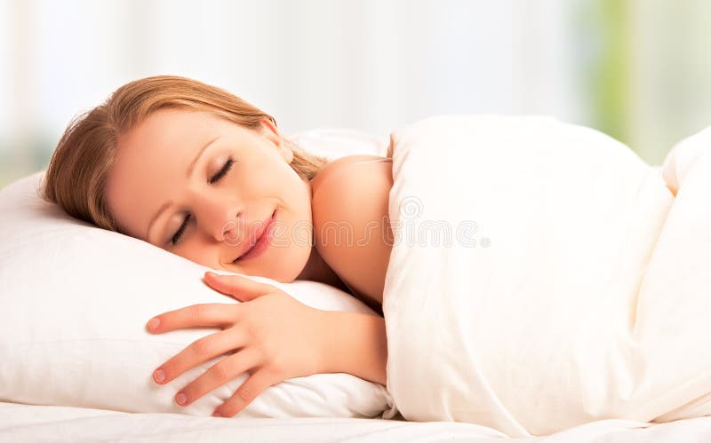 Giovane e bella donna che dorme e sorride nel sonno nel letto.