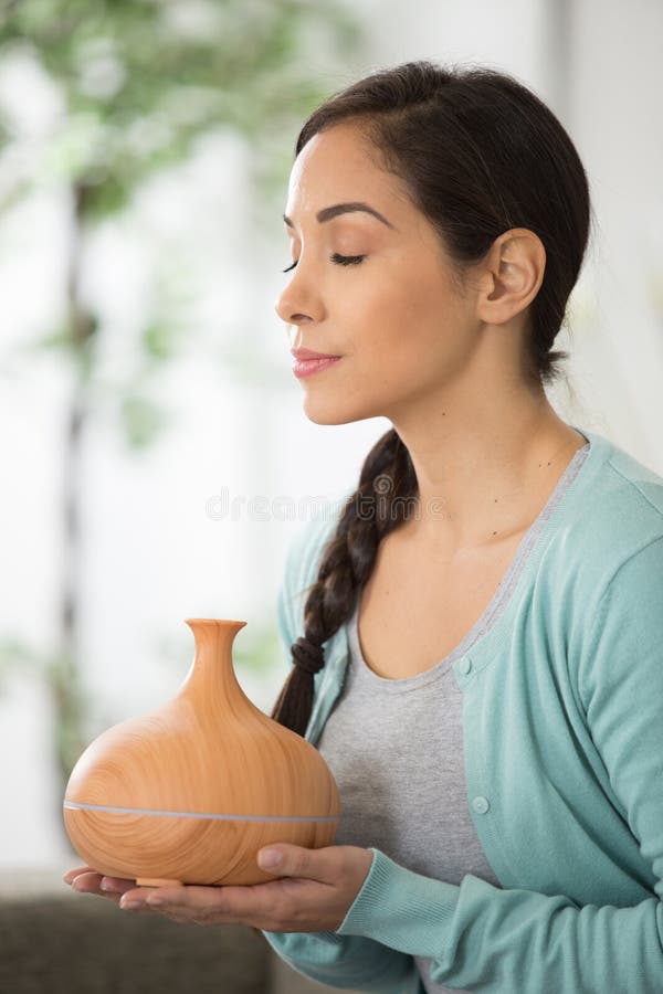 Beautiful woman smelling steam from aroma diffuser stock photo