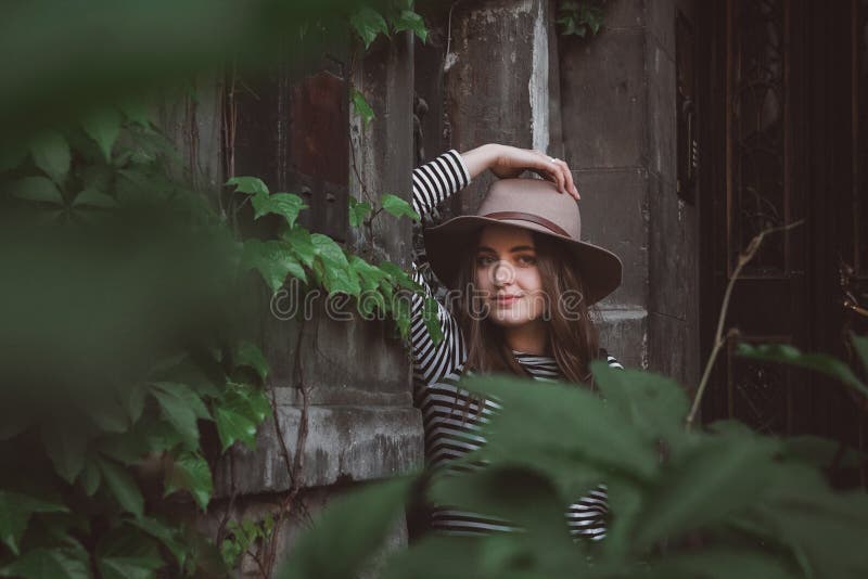 Beautiful woman in a striped shirt holding her hat and looking at a camera. stock photo Beautiful woman in a striped shirt holding her hat and looking at a camera. stock photo